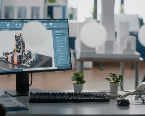 Close up of monitor with 3d building and construction layout on table in office. Urban real estate structure on computer to plan architectural development project. Graphic design